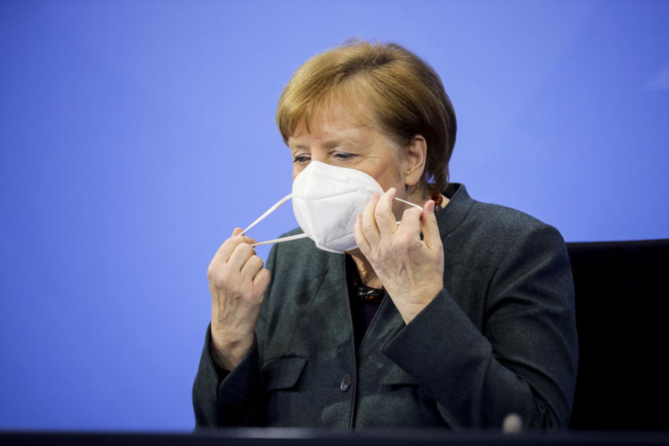 German Chancellor Angela Merkel takes off a face mask as she attends a news conference on further coronavirus measures, at the Chancellery in Berlin, Germany, Tuesday Jan. 19, 2021. (Hannibal Hanschke/Pool via AP)