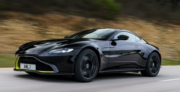 A black Aston Martin Vantage, a low-slung two-seat sports car, on a mountain road.