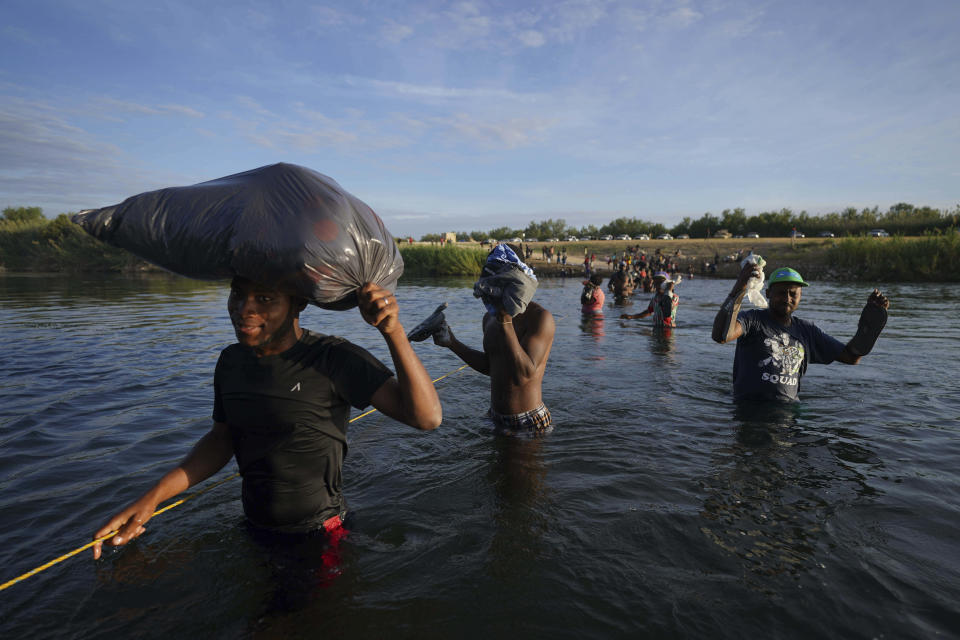 Migrants, many from Haiti, wade across the Rio Grande river to leave Del Rio, Texas, and return to Ciudad Acuna, Mexico, early Wednesday, Sept. 22, 2021, some to avoid possible deportation from the U.S. and others to load up with supplies. (AP Photo/Fernando Llano)