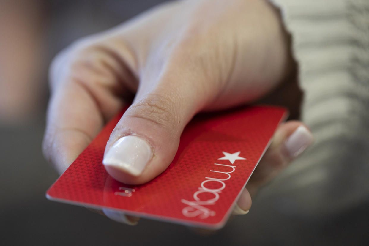 A woman holds a red Macy's card.