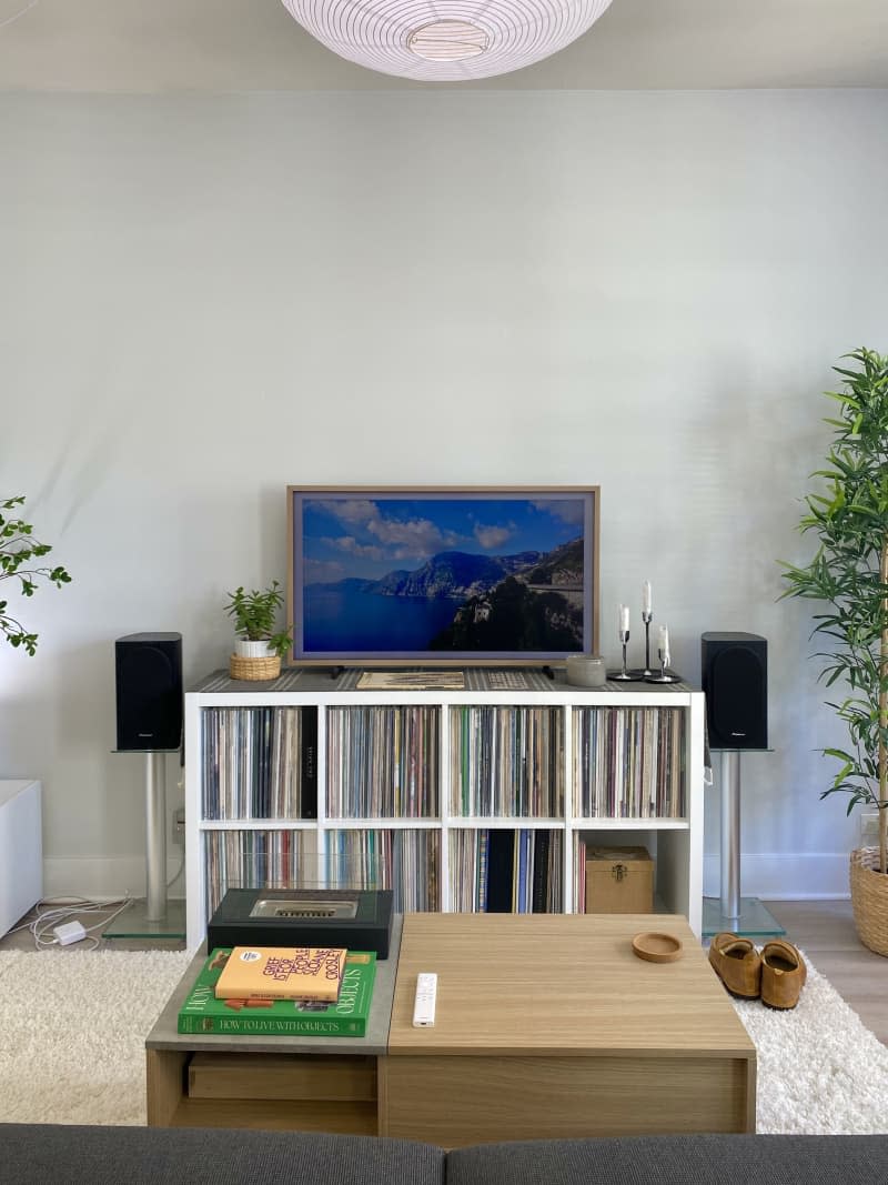 A media console full of records, tv, and speakers on a stand.