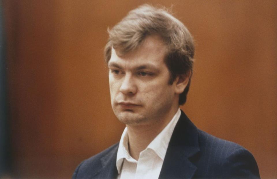 jeffrey dahmer wearing a blue suit and white shirt and looking out of frame