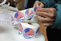 FILE - In this Tuesday, Nov. 6, 2018 file photo, a voter peels off an "I Voted" sticker after casting her ballot in Mt. Kisco, N.Y. On Friday, Jan. 17, 2020, The Associated Press reported on stories circulating online incorrectly asserting that the New York State Senate passed a bill that would “automatically register illegal immigrants to vote.” In January 2020, the Senate passed legislation that would automatically register people to vote when they submit applications to state agencies like the Department of Motor Vehicles. The AP reported that lawmakers noticed a mistake during the session’s final days of 2019 prompting a revision which includes language that prohibits state agencies from sending applications to the state board of elections from people who are ineligible to vote. (AP Photo/Richard Drew)