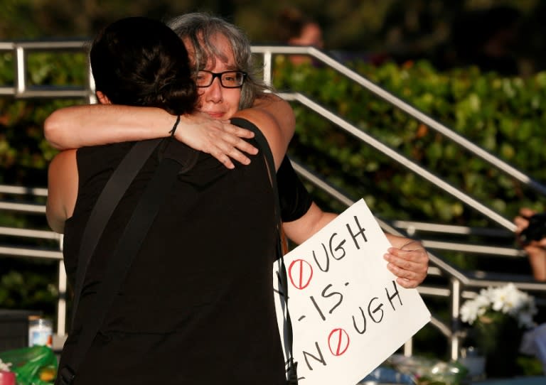 Mourners hug after placing flowers on a makeshift memorial for the victims of the shooting at a Florida high school