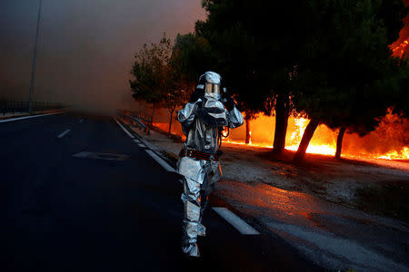A firefighter wears a flame resistant uniform as wildfire burns in the town of Rafina, near Athens, Greece, July 23, 2018. REUTERS/Costas Baltas