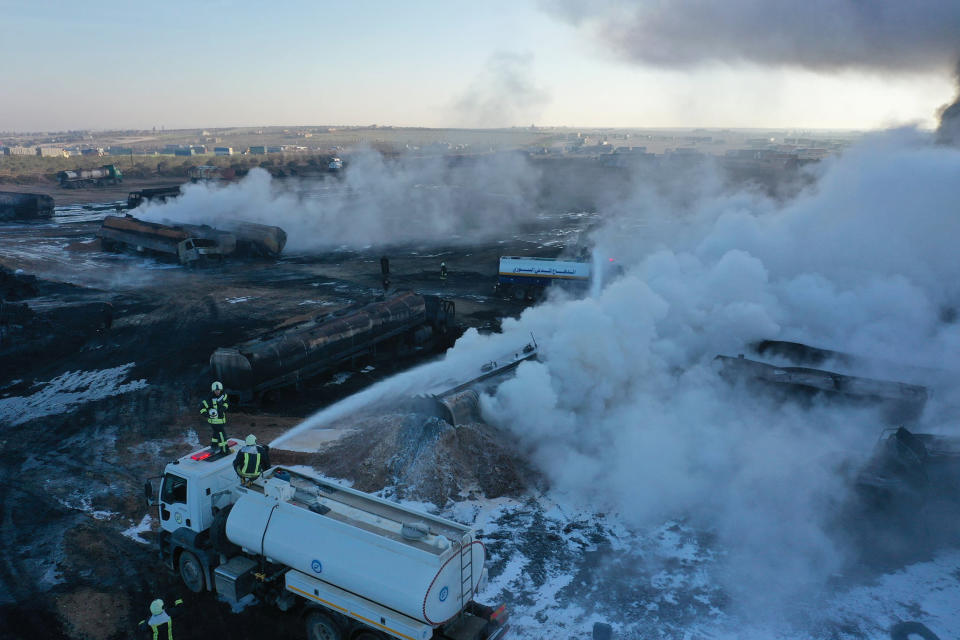 In this photo provided Saturday, March 6, 2021 by the Syrian Civil Defense group known as the White Helmets, Civil Defense workers extinguish burning oil tanker trucks after a suspected missile strike around the towns of Jarablus and al-Bab, near the border with Turkey, in western Aleppo province, Syria. Syrian opposition groups and the Syrian Observatory for Human Rights, based in Britain blamed Russia for the Friday night strikes. (Syrian Civil Defense White Helmets via AP)