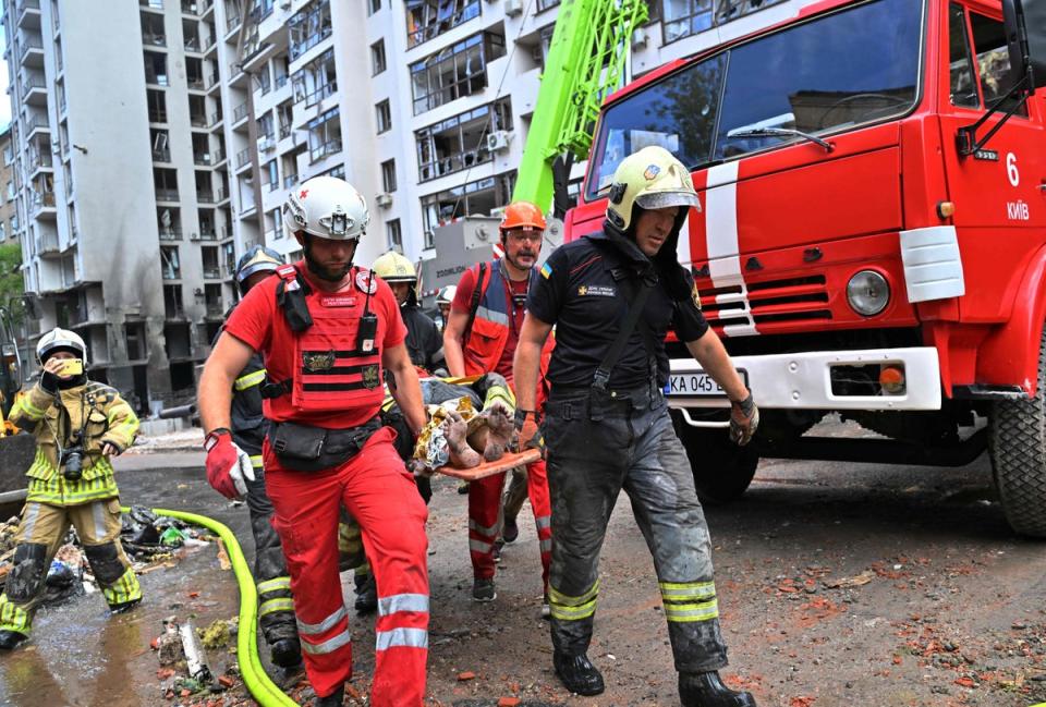 Emergency workers take a woman injured in the attack to safety (AFP via Getty Images)