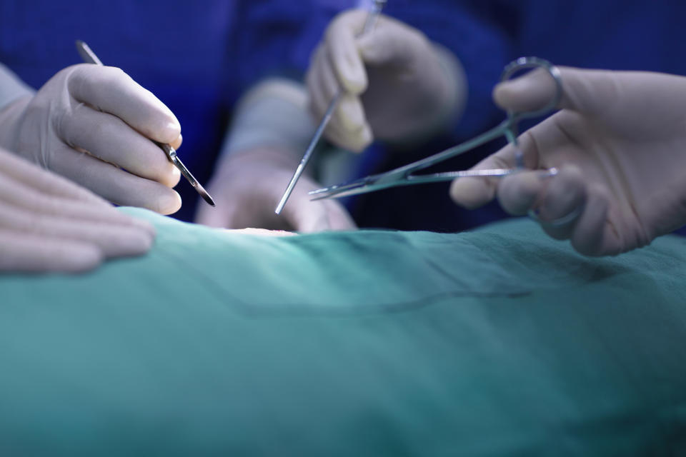 People's hands holding surgical tools and performing surgery