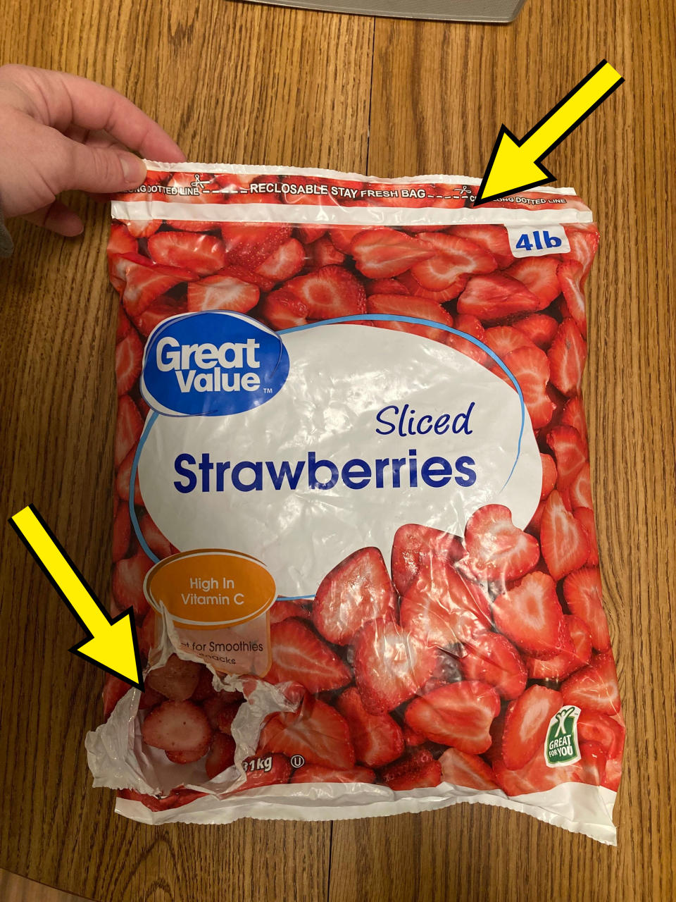 A hand holding a Great Value brand bag of sliced strawberries. Text highlights 'High in Vitamin C' and 'for Smoothies.'