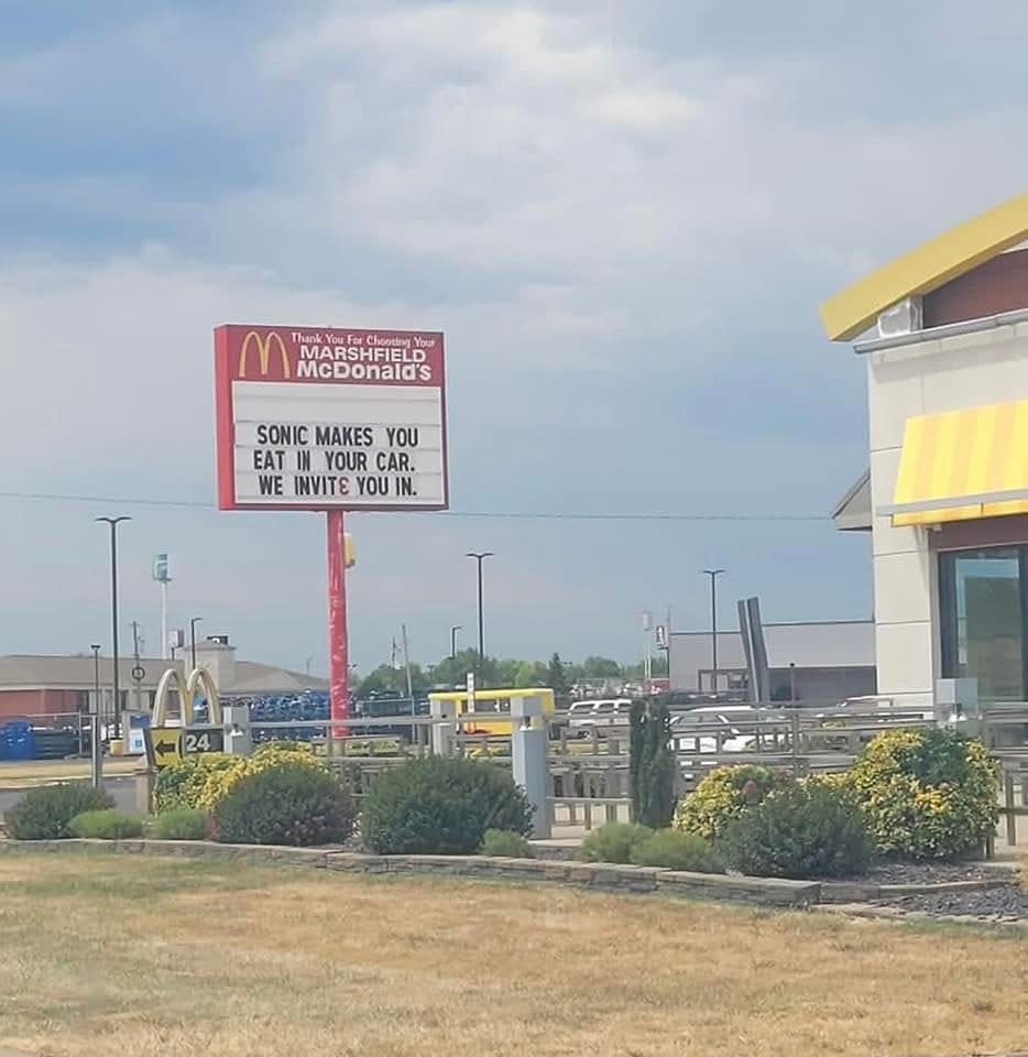 a McDonald's sign that says "Sonic makes you eat in your car, we invite you in"
