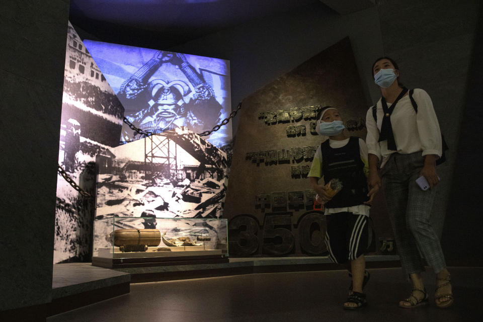 Visitors wearing mask to protect from the coronavirus past by an exhibition on the War of Resistance against Japanese Aggression in Beijing on Thursday, Sept. 3, 2020. China on Thursday commemorated the 75th anniversary of the end of World War II in the Pacific, during which it endured a brutal invasion and occupation of much of its territory by Japan. (AP Photo/Ng Han Guan)