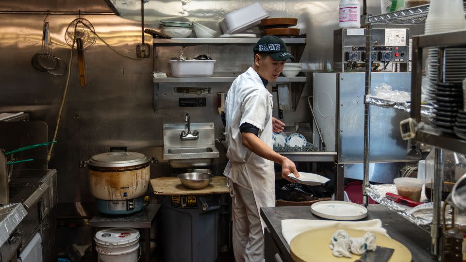 Jiang Zhen cleans dishes at a Chinese restaurant in Queens. - Yong Xiong/CNN