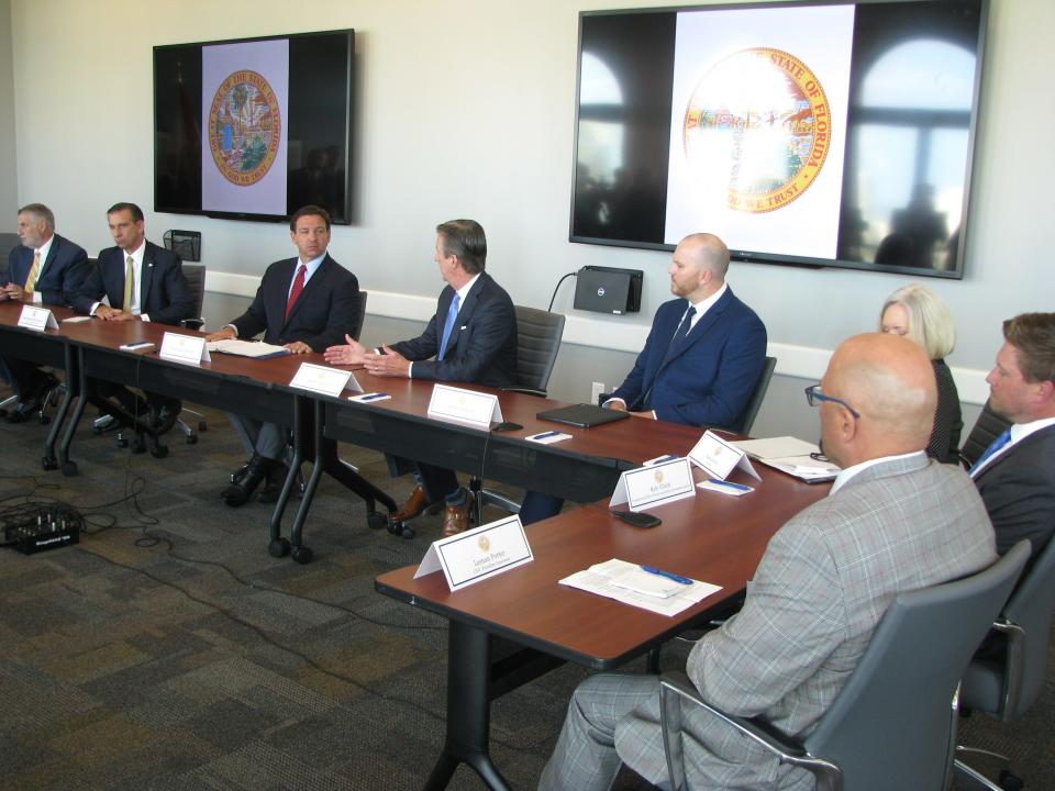 Gov. Ron DeSantis, pictured in a red tie, discusses property insurance legislation before signing the bill at an event in downtown Sarasota Friday, June 11.