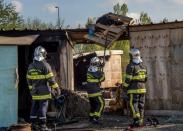 French firemen inspect a burnt hut at the Grande-Synthe migrant camp on the outskirts of Dunkirk, on April 11, 2017