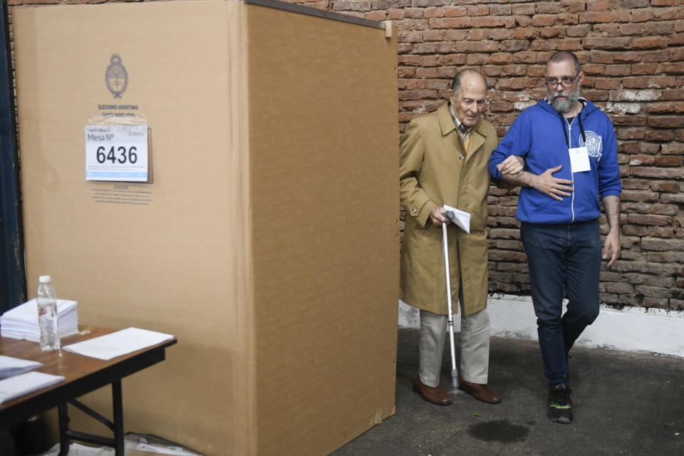 A voter is helped by an electoral official staff after choosing his preferences during general elections in Buenos Aires, Argentina, Sunday, Oct. 22, 2023. (AP Photo/Gustavo Garello)