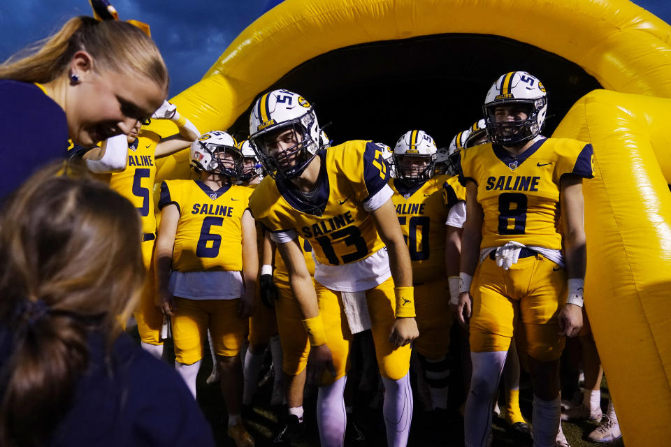 Saline High School quarterback CJ Carr (13) meets a fan before a football game Friday, Oct. 27, 2023, in Saline, Mich. Carr will be among the hundreds of football players to sign a national letter of intent this week, sealing his commitment to join Notre Dame, but no one has a story quite the same. (AP Photo/Carlos Osorio)