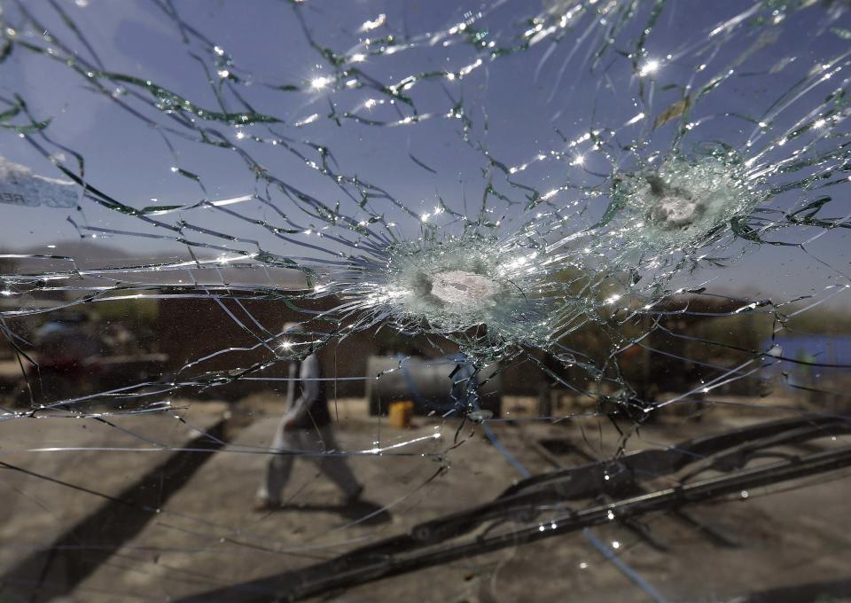 An Afghan man walks next to the cracked side window of a vehicle after was hit by a remote-controlled bomb in Kabul July 15, 2014. A remote-controlled bomb planted at the side of a road hit a government employee's vehicle, killing two people and wounding five, a police officer said. (REUTERS/Omar Sobhani)