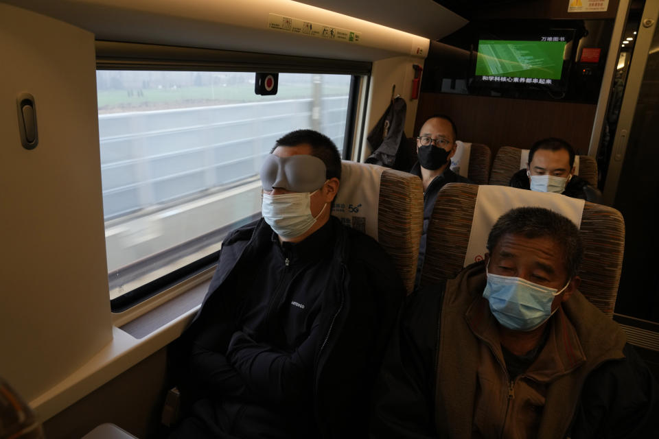 Passengers on board a high speed train from Beijing to Shanghai wear masks to curb the spread of coronavirus past near Nanjing in eastern China's Jiangsu Province on Dec. 16, 2021. China’s attitude toward the virus, omicron or not, is to stop transmission in its tracks, and the country appears to be getting even tougher with the approach of the Beijing Winter Olympics in February. (AP Photo/Ng Han Guan)