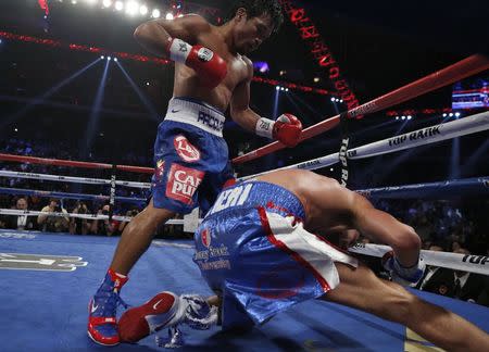 Chris Algieri of the U.S. falls as he takes a punch from Manny Pacquiao (L) of the Philippines during their World Boxing Organisation (WBO) 12-round welterweight title fight at the Venetian Macao hotel in Macau November 23, 2014. REUTERS/Tyrone Siu