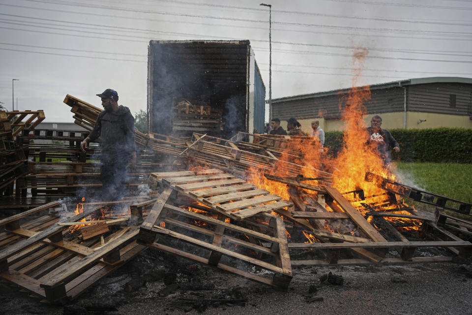 Prison workers burn wooden pallets during a protest in front of the Corbas prison, outside Lyon, France, Wednesday, May 15, 2024 . A massive manhunt was underway in France on Wednesday for an armed gang that ambushed a prison convoy, killing two prison officers, seriously injuring three others and springing the inmate they were escorting. (AP Photo/Laurent Cipriani)