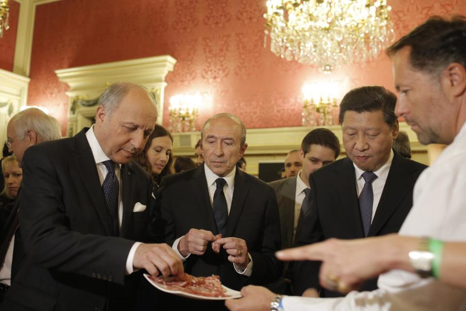 French foreign minister Laurent Fabius, left, Lyon's mayor Gerard Collomb, center, and Chinese President Xi Jinping, second from right, taste local food before a dinner at the town hall in Lyon, central France, Tuesday, March 25, 2014. Xi Jinping arrived in France for a three-day state visit. (AP Photo/Laurent Cipriani, Pool)