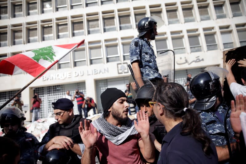 Police officers stand guard after protesters knocked down the fencing as they demonstrate outside of Lebanon Central Bank during ongoing anti-government protests in Beirut