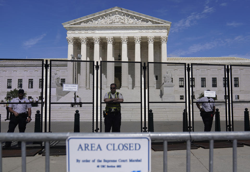 U.S. Capitol Police officers stand post behind the temporary anti-scaling fence surrounding the U.S. Supreme Court, on Tuesday, June 28, 2022, in Washington. The Supreme Court has put on hold a lower court ruling that Louisiana must draw new congressional districts before the 2022 elections to increase Black voting power. (AP Photo/Mariam Zuhaib)