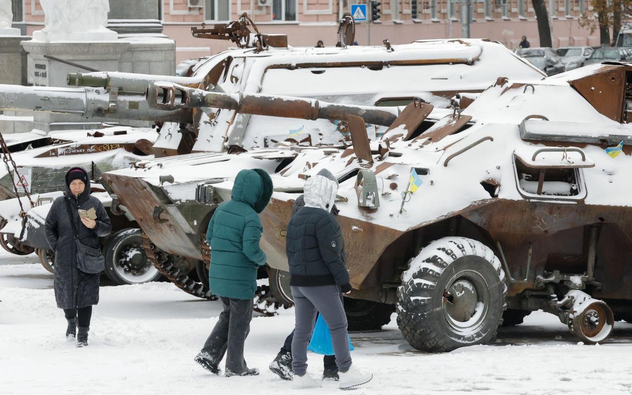People walk past snow covered, destroyed Russian machinery displayed in Kyiv, Ukraine,