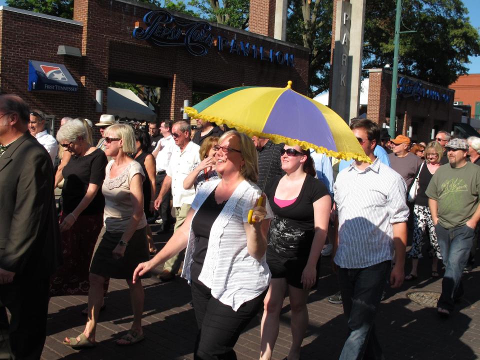 Jean Crawford, a niece of Donald "Duck" Dunn, walks with a parasol in a funeral parade down Memphis' Beale Street honoring the late soul bassist on Wednesday, May 23, 2012 in Memphis, Tenn. More than 100 fans walked and danced down the Memphis drag during the New Orleans-style parade to remember Dunn, who died May 13 at age 70 while on tour in Japan. (AP Photo/Adrian Sainz)