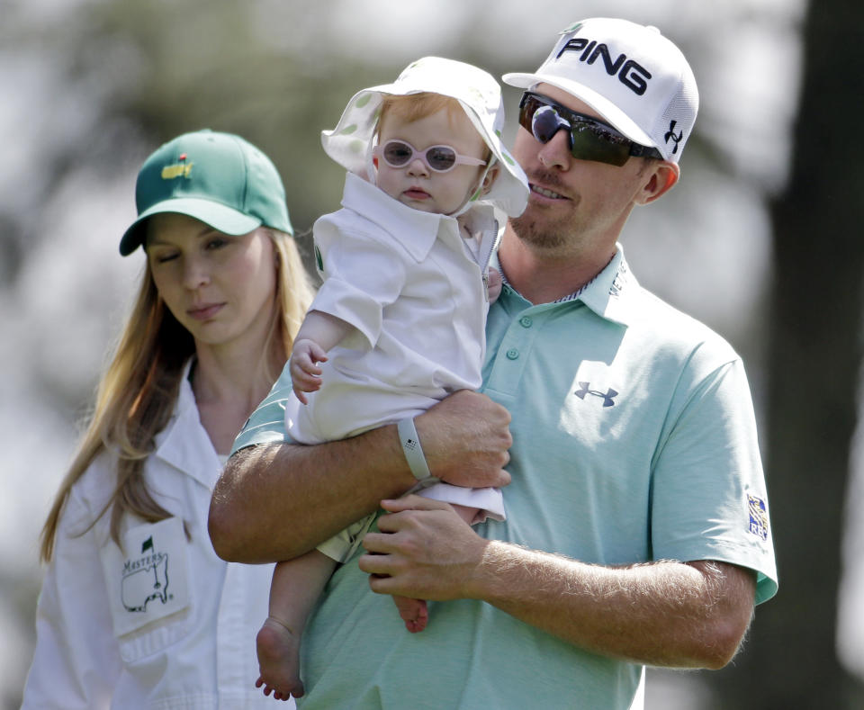 Hunter Mahan carries his daughter Zoe as he walks down the first fairway with his wife Kandi during the par three competition at the Masters golf tournament Wednesday, April 9, 2014, in Augusta, Ga. (AP Photo/Darron Cummings)