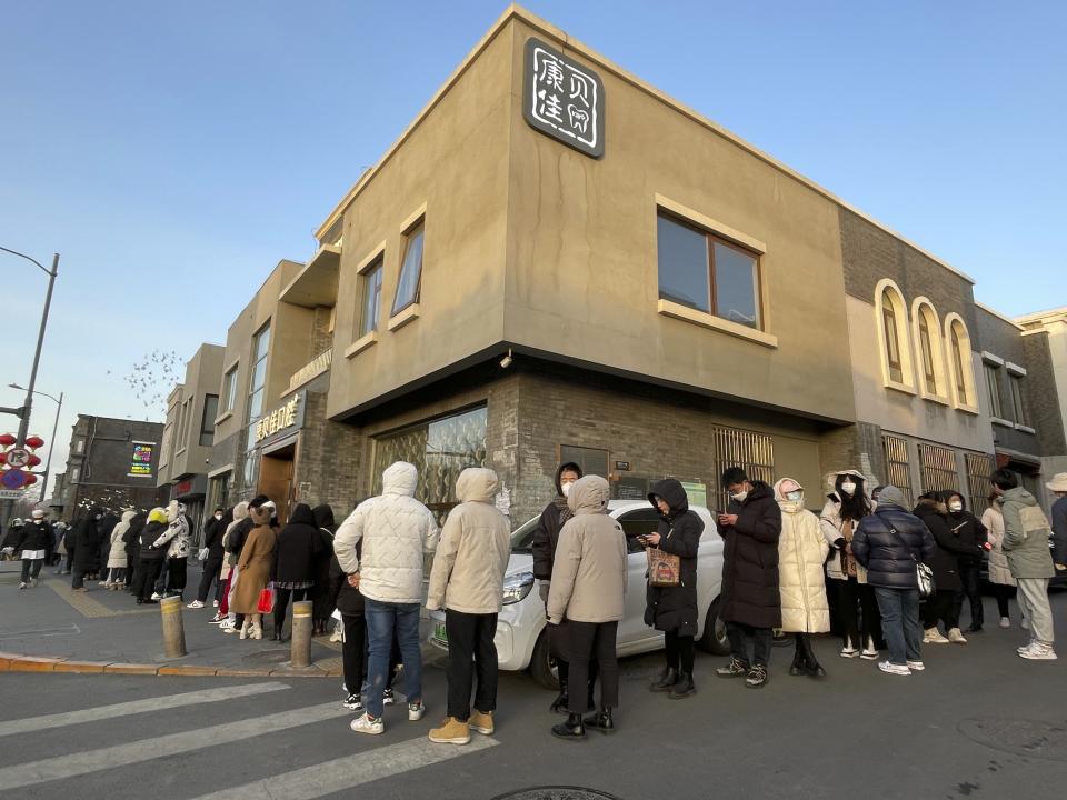 Customers wait in a line in sub-zero temperatures outside the flagship store Daoxiangcun, one of Beijing’s best-known Chinese bakeries, to buy new year gift boxes on Jan. 14, 2023. (AP Photo/Caroline Chen)