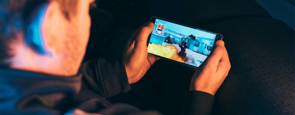 Leisure gamer plays action video game on mobile phone at night