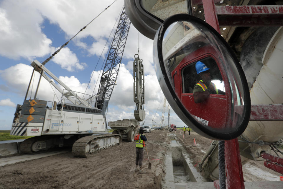 In this Friday, Oct. 25, 2019, photo, workers use heavy equipment to strengthen the 1930s-era Herbert Hoover Dike ringing Lake Okeechobee, at South Bay, Fla. (AP Photo/Robert F. Bukaty)