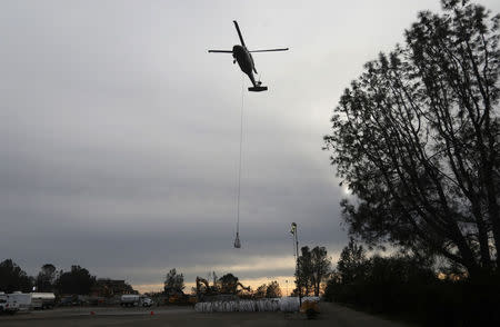 A helicopter takes off with a load of rocks to haul to the Lake Oroville Dam after an evacuation was ordered for communities downstream from the dam in Oroville, California, U.S. February 13, 2017. REUTERS/Jim Urquhart