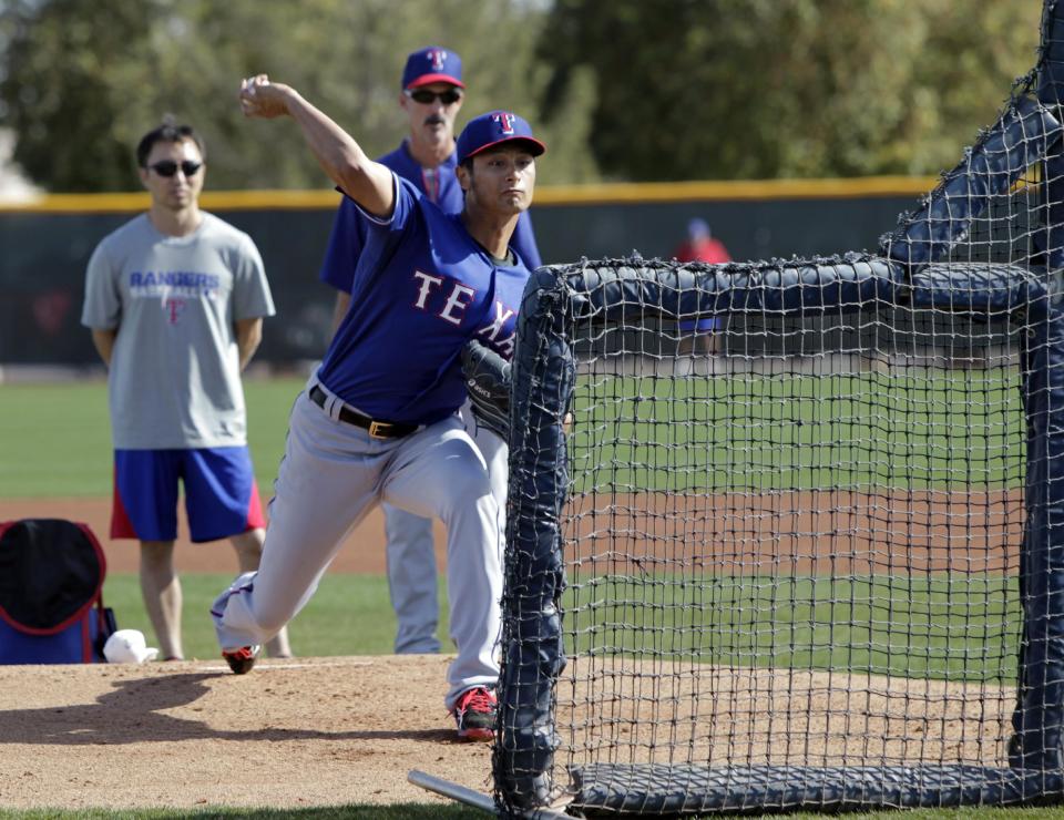 Texas Rangers starting pitcher Yu Darvish, of Japan, throws batting practice as his translator Kenji Nimura, left rear, and pitching coach Mike Maddux, right rear, watch during spring training baseball practice, Tuesday, Feb. 18, 2014, in Surprise, Ariz. (AP Photo/Tony Gutierrez)