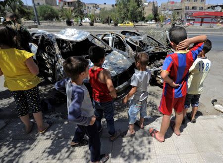 Children look at the wreckage of vehicles at a blast site in the Baytara traffic circle near the Old City of Damascus, Syria July 2, 2017. REUTERS/Omar Sanadiki