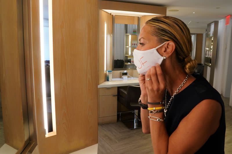 Suelyn Farel adjusts her mask on the first day of the phase two re-opening of businesses following the outbreak of the coronavirus disease (COVID-19), in the Manhattan borough of New York City