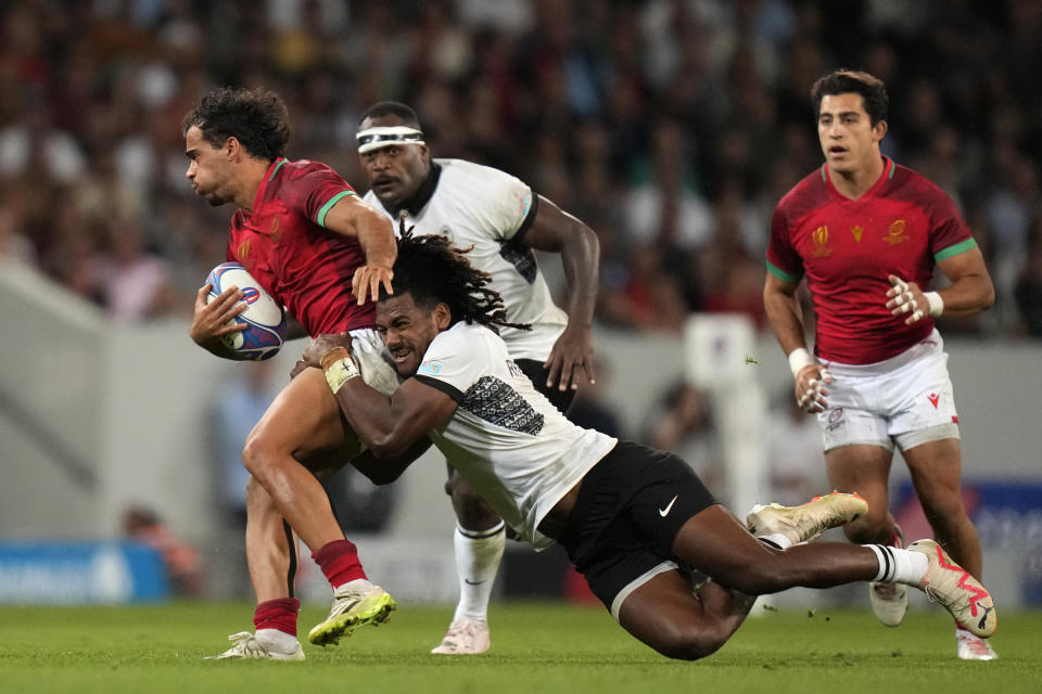 Portugal's Manuel Cardoso, left, is tackled by Pinto Fiji's Selestino Ravutaumada during the Rugby World Cup Pool C match between Fiji and Portugal, at the Stadium de Toulouse in Toulouse, France, Sunday, Oct. 8, 2023. (AP Photo/Pavel Golovkin)