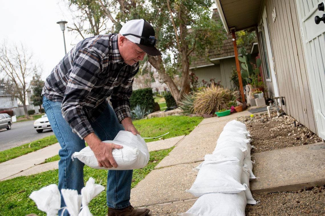 Chief Operating Officer of Leap Carpenter Kemps Insurance, Dave Cribb, 64, of Oakdale, places sandbags along the front of the home of one of the company’s employees on Driftwood Drive, while preparing for upcoming rainstorms in Merced, Calif., on Thursday, March 9, 2023. According to the resident, the home took on about five inches of water during the previous heavy rains and flooding.