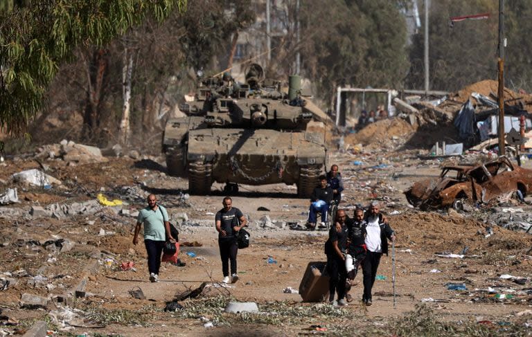 Palestinos que huyen hacia el norte por la carretera de Salaheddine, en el distrito de Zeitoun, en la periferia sur de la ciudad de Gaza, pasan junto a tanques del ejército israelí el 24 de noviembre de 2023