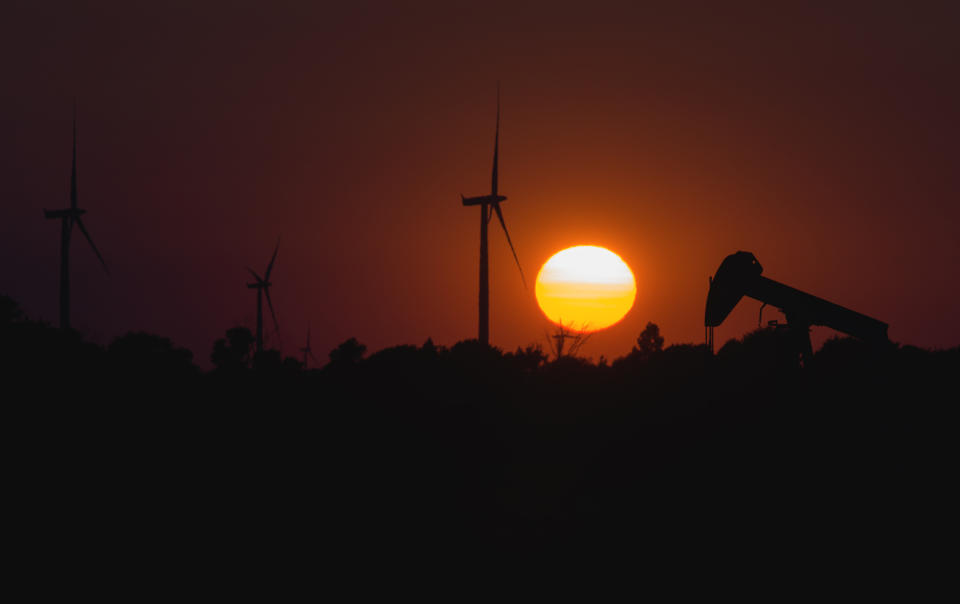 Oil pumps and wind turbines at sunset.