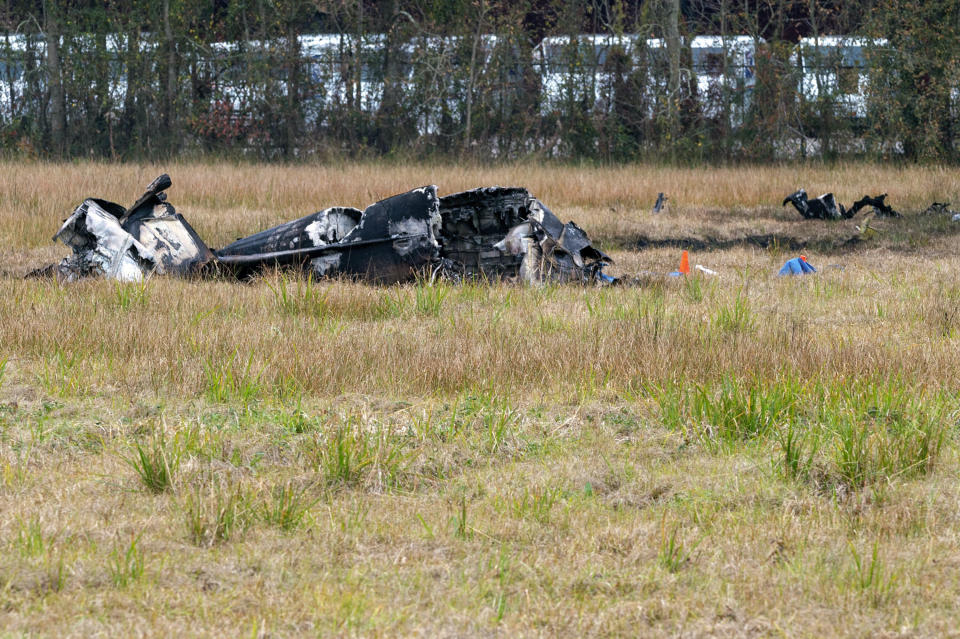 A view of the burnt wreckage of a small plane that crashed into the parking lot of a post office is shown, at left, in Lafayette, La., Saturday, Dec. 28, 2019. Several people died in the crash. (Scott Clause/The Lafayette Advertiser via AP)