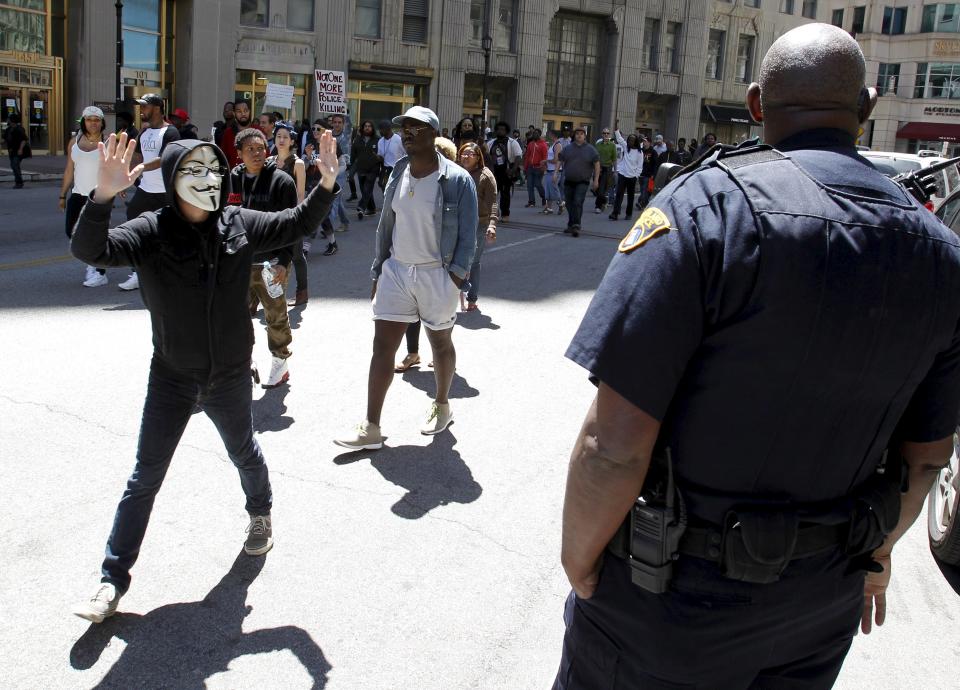 A protester with his hands up walks by a Cleveland police officer following a not guilty verdict for Cleveland police officer Michael Brelo on manslaughter charges, in Cleveland, Ohio, May 23, 2015. Brelo was found not guilty on Saturday in the shooting deaths of an unarmed black man and a woman after a high-speed car chase in 2012, one in a series of cases that have raised questions over police conduct and race relations in the U.S. (REUTERS/Aaron Josefczyk)