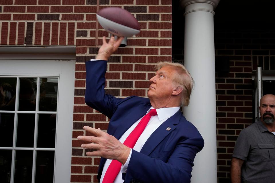 Former President Donald Trump throws a football to the crowd during a visit to the Alpha Gamma Rho, agricultural fraternity, at Iowa State University before an NCAA college football game between Iowa State and Iowa on Sept. 9, in Ames, Iowa.