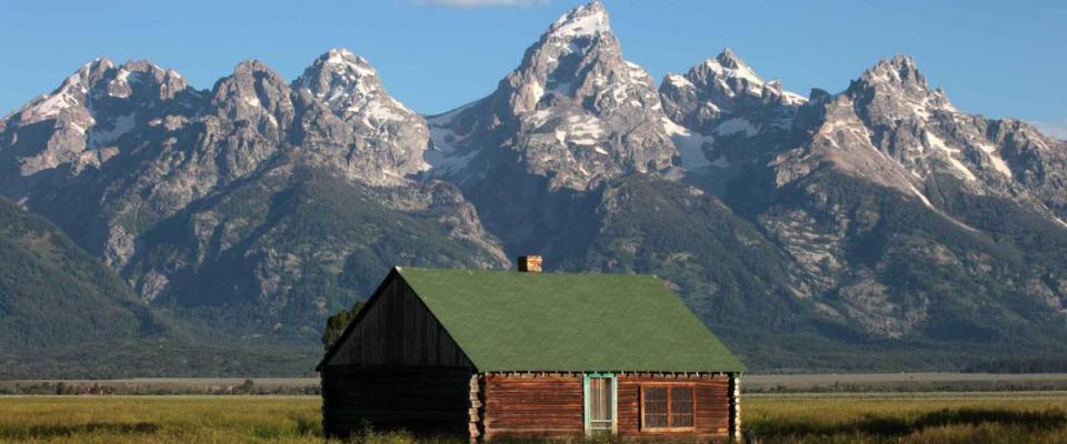 A weathered home sits against the backdrop of the Grand Tetons in Wyoming