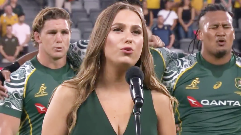 Singer Olivia Fox is pictured in front of Wallabies captain Michael Hooper and hooker Brandon Paenga-Amosa.