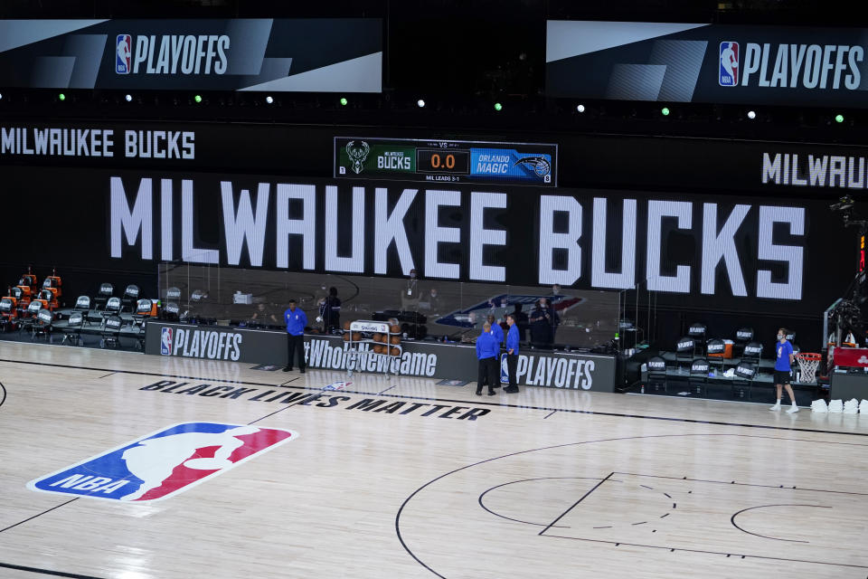 Officials stand beside an empty court at the scheduled start of an NBA game between the Milwaukee Bucks and the Orlando Magic on Aug. 26, 2020. The Milwaukee Bucks didn't take the floor in protest against racial injustice and the shooting of Jacob Blake, a Black man, by police in Kenosha, Wisconsin. (AP)