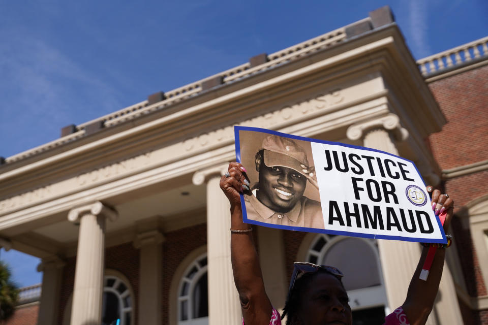 A demonstrator in front of Glynn County Courthouse holds a sign with a photo of Ahmaud Arbery and the words Justice for Ahmaud.