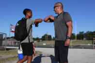 Head football coach Bob Wager, right, and sophomore safety Cameron Conley greet each other at the re-opening of strength and conditioning camp at Arlington Martin High School, Thursday, June 18, 2020, in in Arlington, Texas. While states have been easing the economic and social lockdowns prompted by the coronavirus pandemic, some are now letting high school athletes return for summer workouts before teachers have even figured out how they are going to hold classroom instruction. (AP Photo/LM Otero)