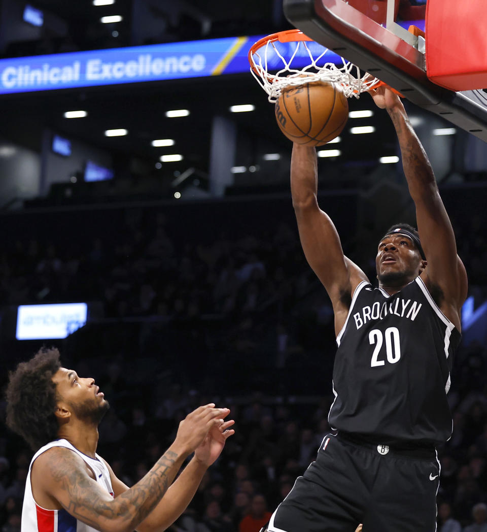 Brooklyn Nets center Day'Ron Sharpe (20) dunks next to Detroit Pistons guard Cade Cunningham during the first half of an NBA basketball game Saturday, Dec. 23, 2023, in New York. (AP Photo/Noah K. Murray)